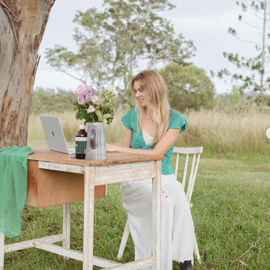 Amy Angus Brisbane naturopath sitting at desk under tree